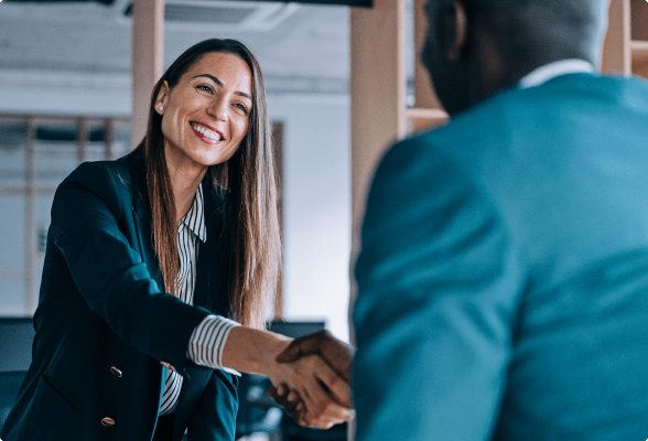 A StoneX Pro representative, a woman in a business suit, shaking hands to solidify a partnership with a client.
